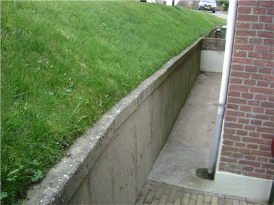 Foto van een grastalud dat eindigt op een keermuur.