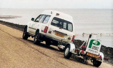 Foto van auto met aanhanger op talud.