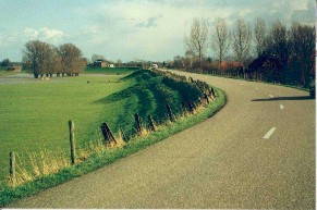 Foto van dijk met links reliëf in het grastalud.